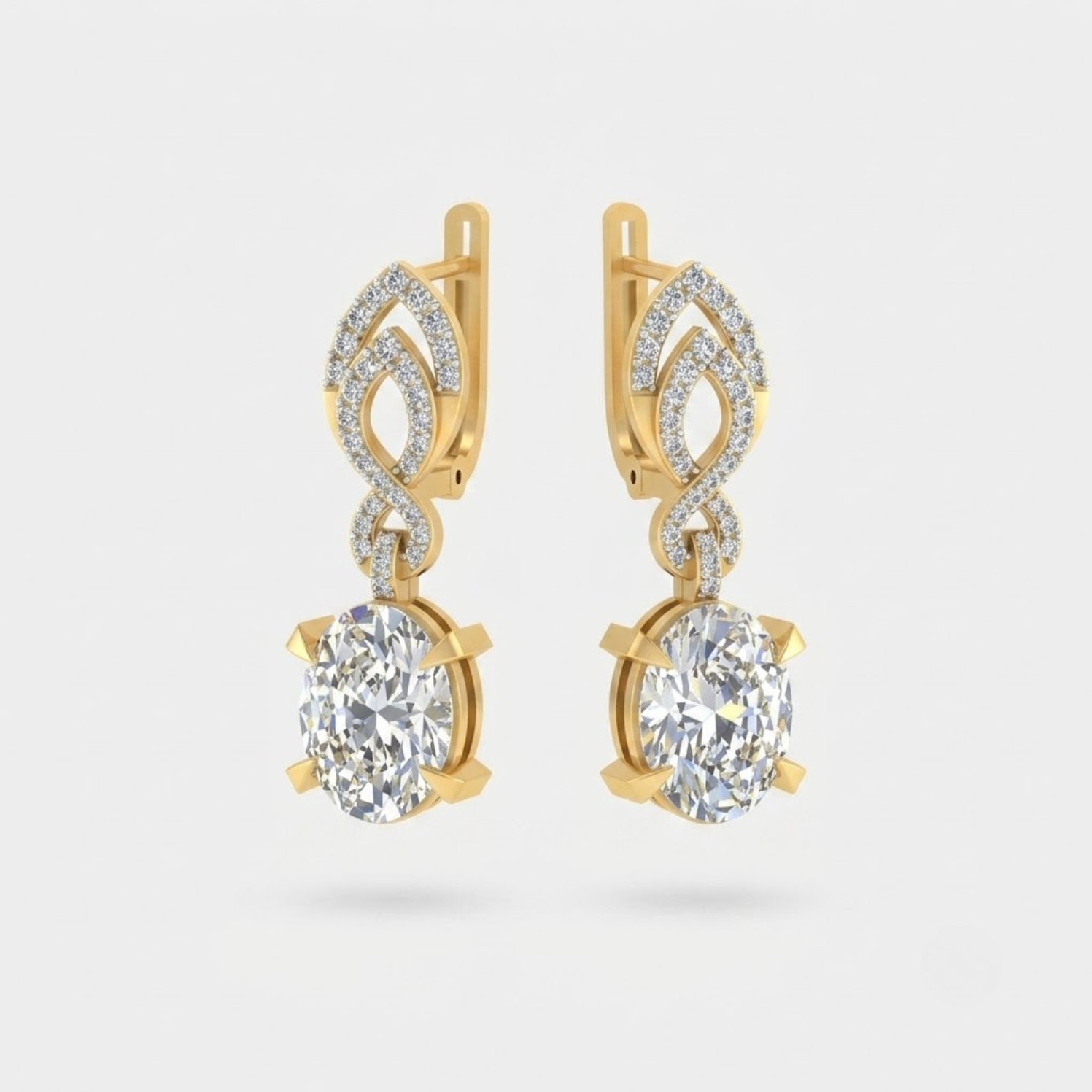 A pair of gold drop earrings featuring large oval clear gemstones in prong settings, with smaller pavé-set stones above in an openwork leaf-like design, shown on a light gray background.