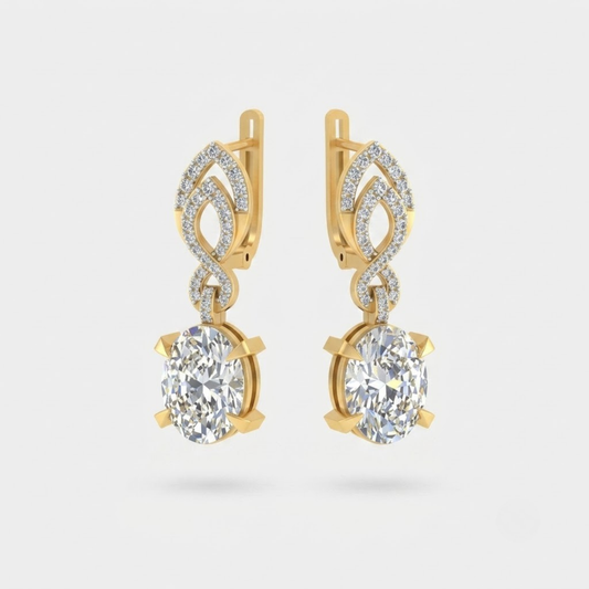 A pair of gold drop earrings featuring large oval clear gemstones in prong settings, with smaller pavé-set stones above in an openwork leaf-like design, shown on a light gray background.
