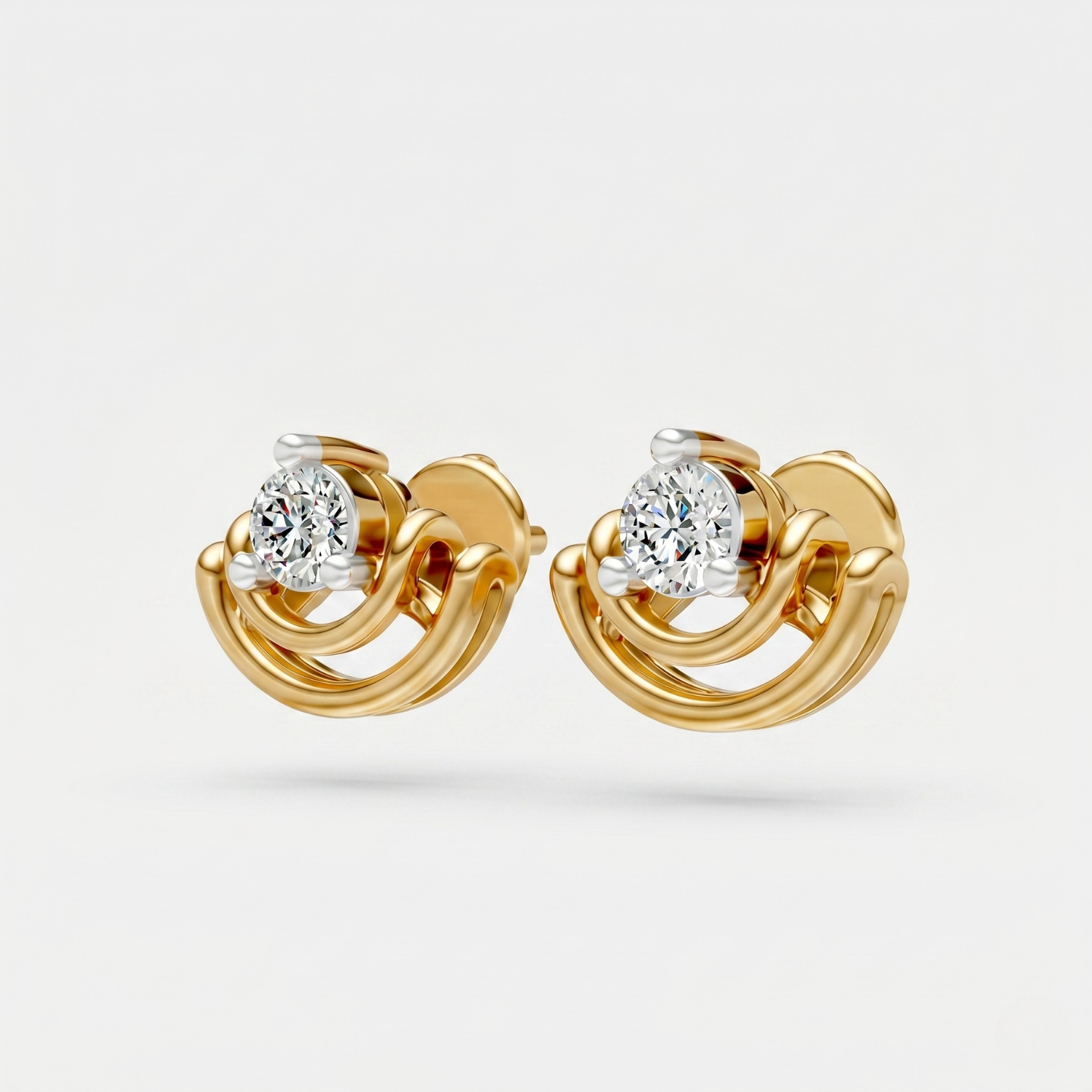 A pair of gold huggie stud earrings with a round-cut clear gemstone in a prong setting, shown on a light gray background.