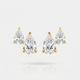 A pair of pear-cut diamond stud earrings in yellow gold settings, displayed on a clean white background with a soft reflection below.