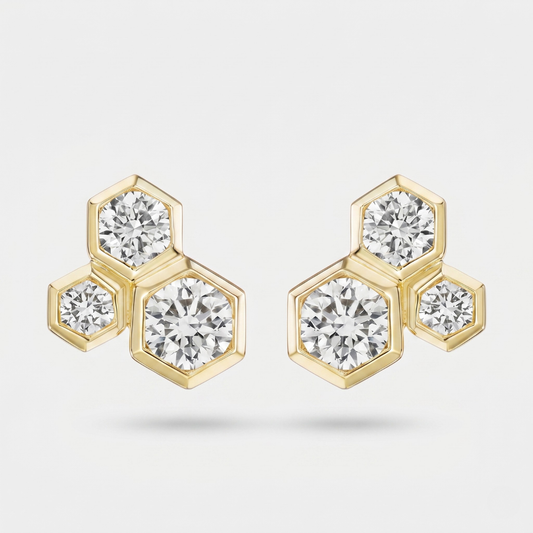A pair of gold hexagonal stud earrings with round-cut clear gemstones, displayed on a light gray background.