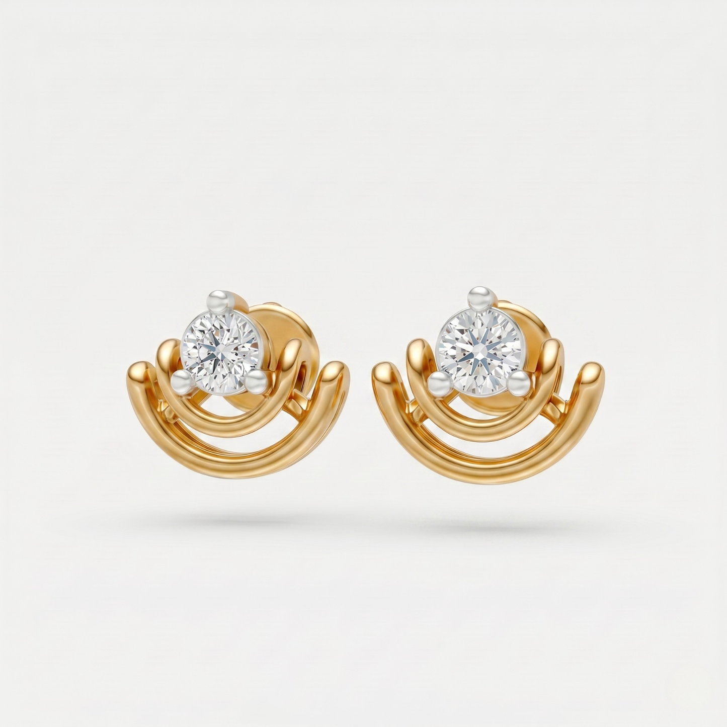 A pair of gold and white gold stud earrings with a central round-cut clear gemstone, set against a light gray background.